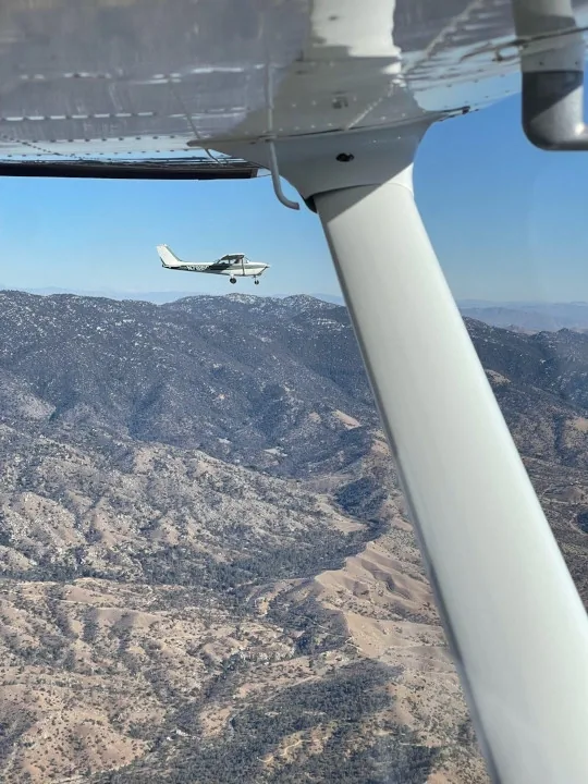 Training aircraft flying over the San Bernardino Mountains north of Redlands Municipal Airport